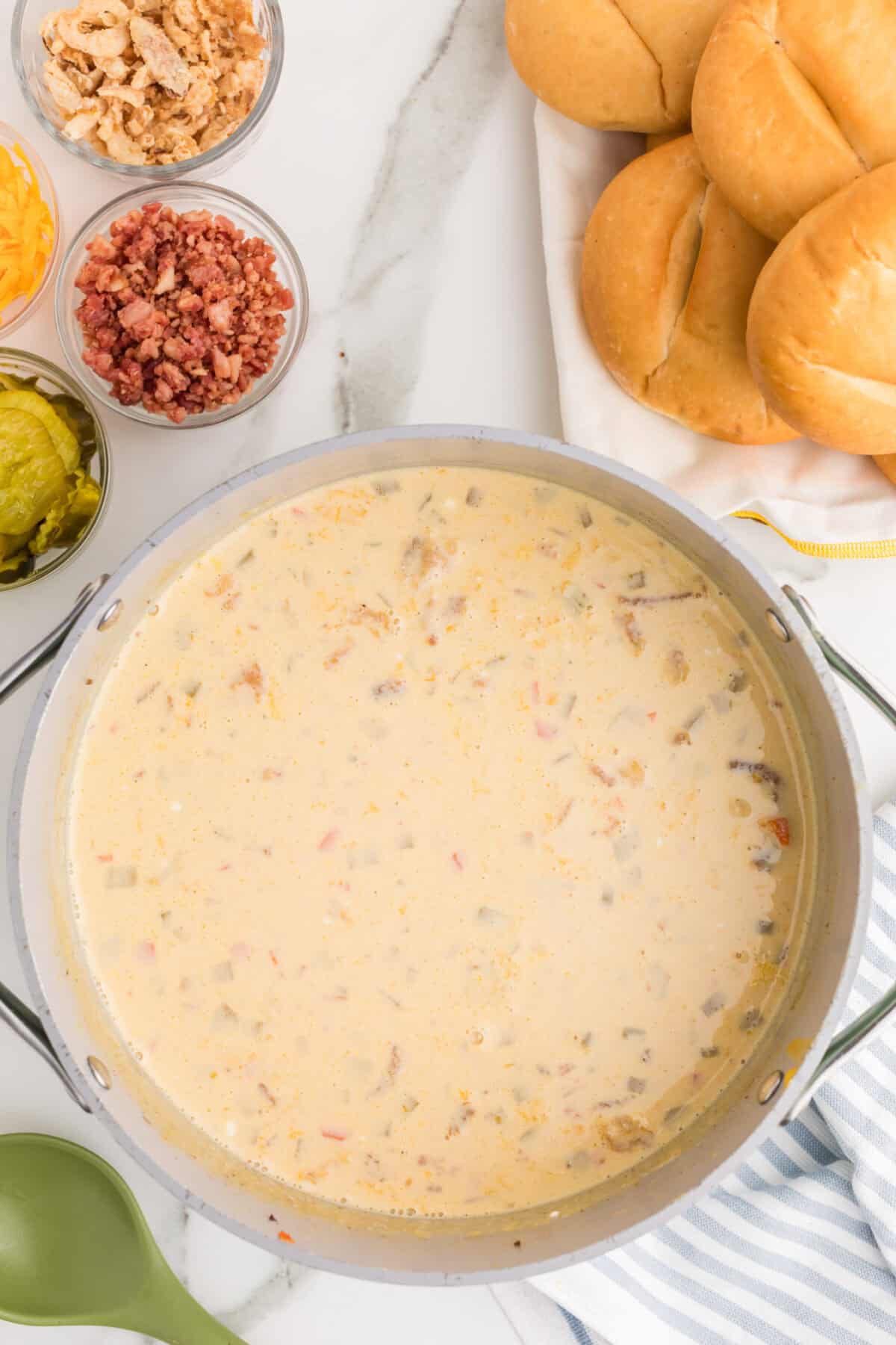 finished cheeseburger soup with small bowls of toppings next to the soup pot
