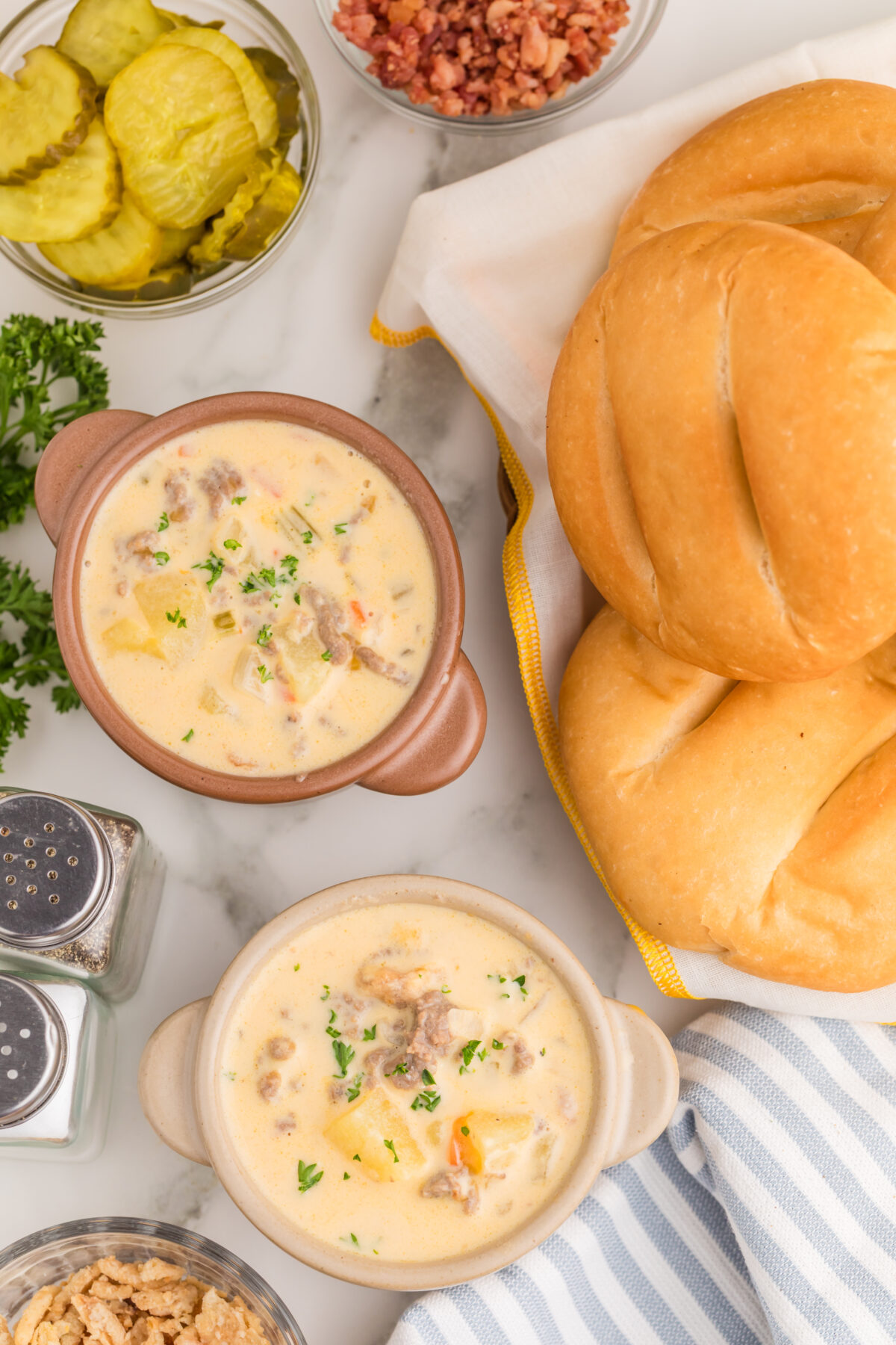 bowls of cheeseburger soup with loaves of bread and toppings