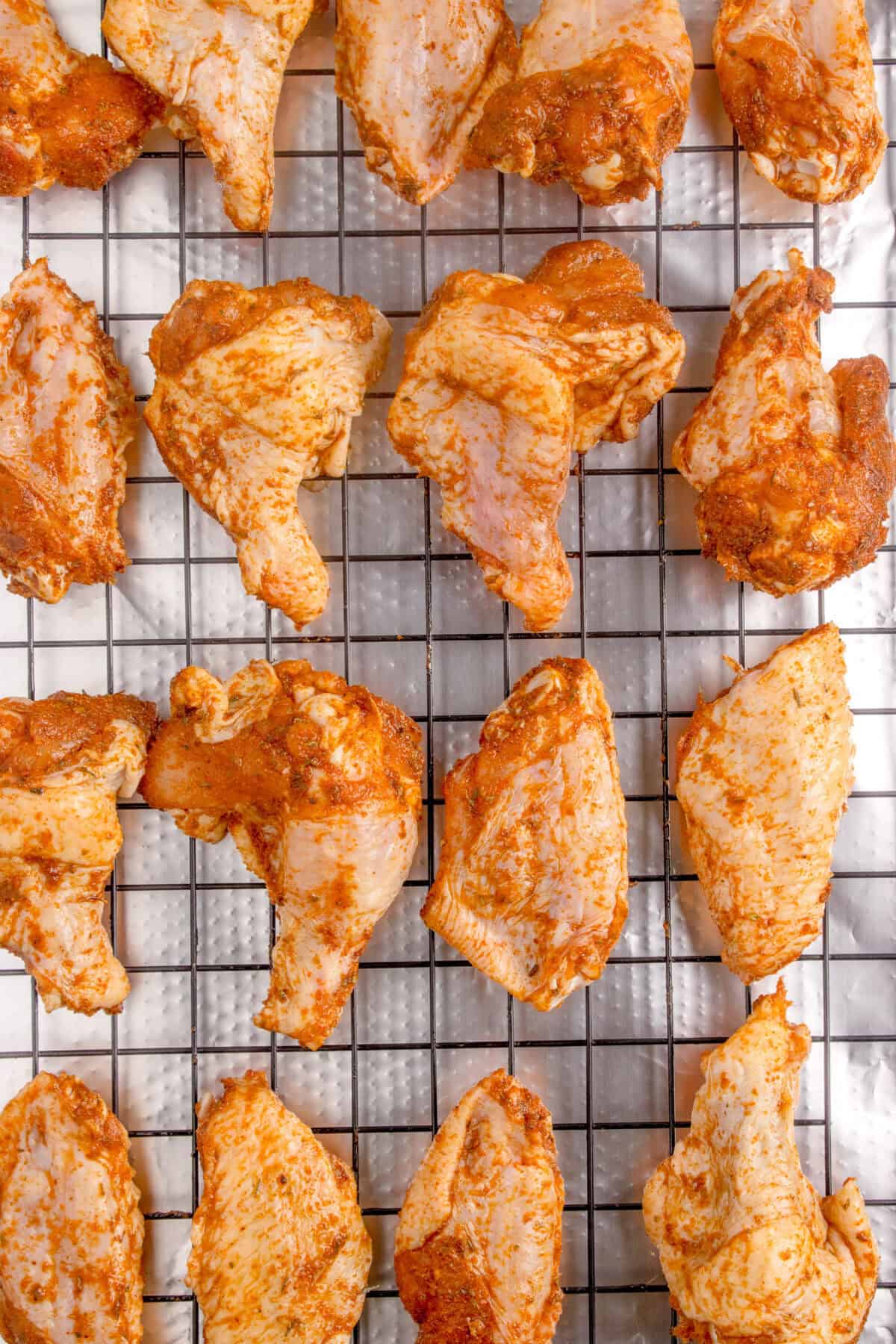 wings with dry rub on a foil lined baking sheet with a wire rack