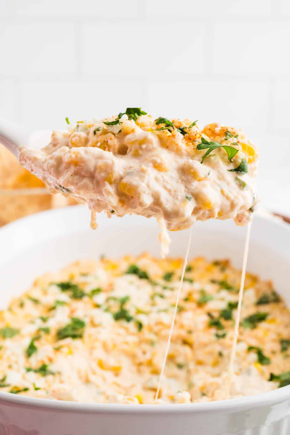 mexican street corn dip on a tortilla chip over a bowl