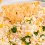 tortilla chip dipped into a bowl of mexican street corn dip