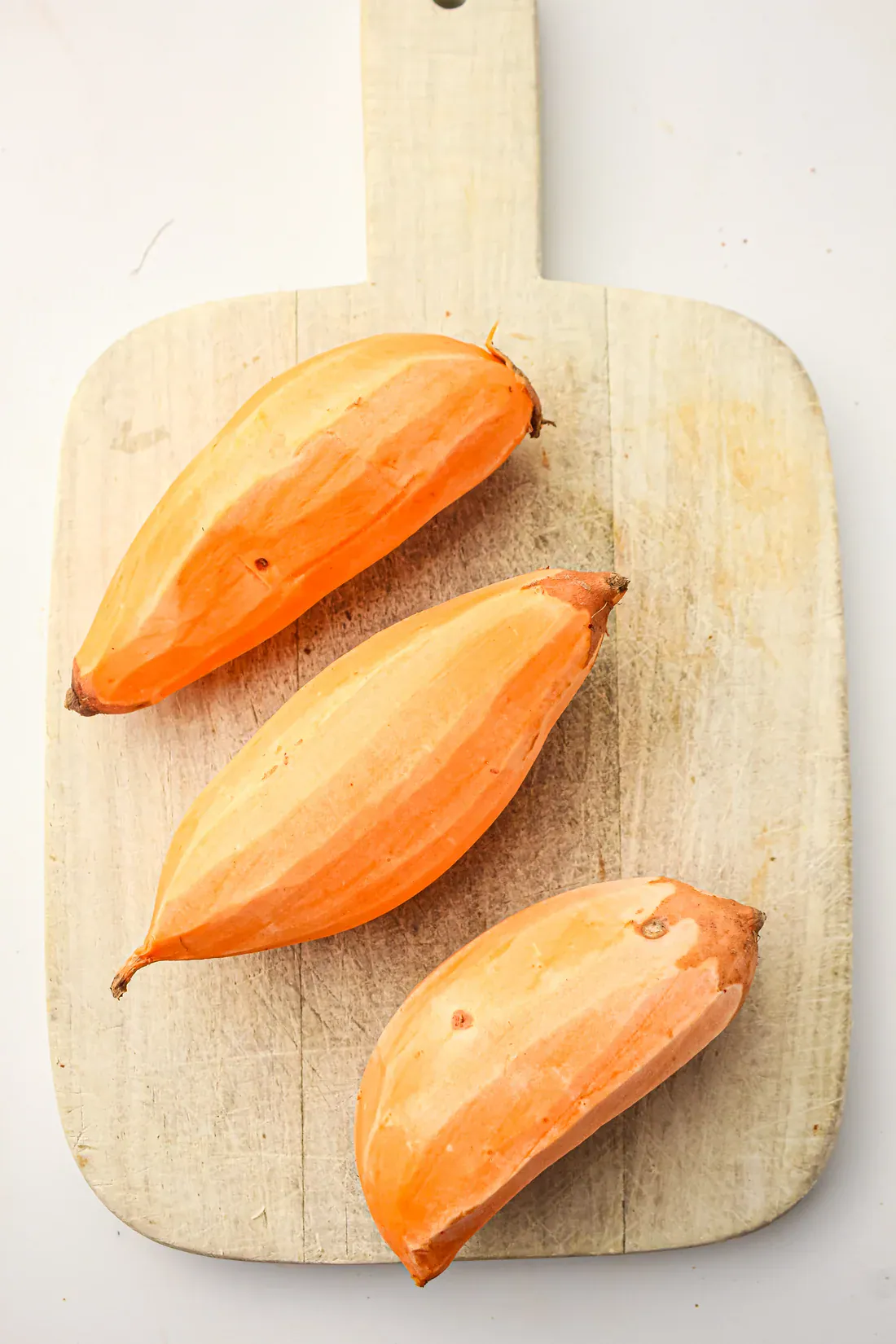 peeled sweet potatoes on a cutting board