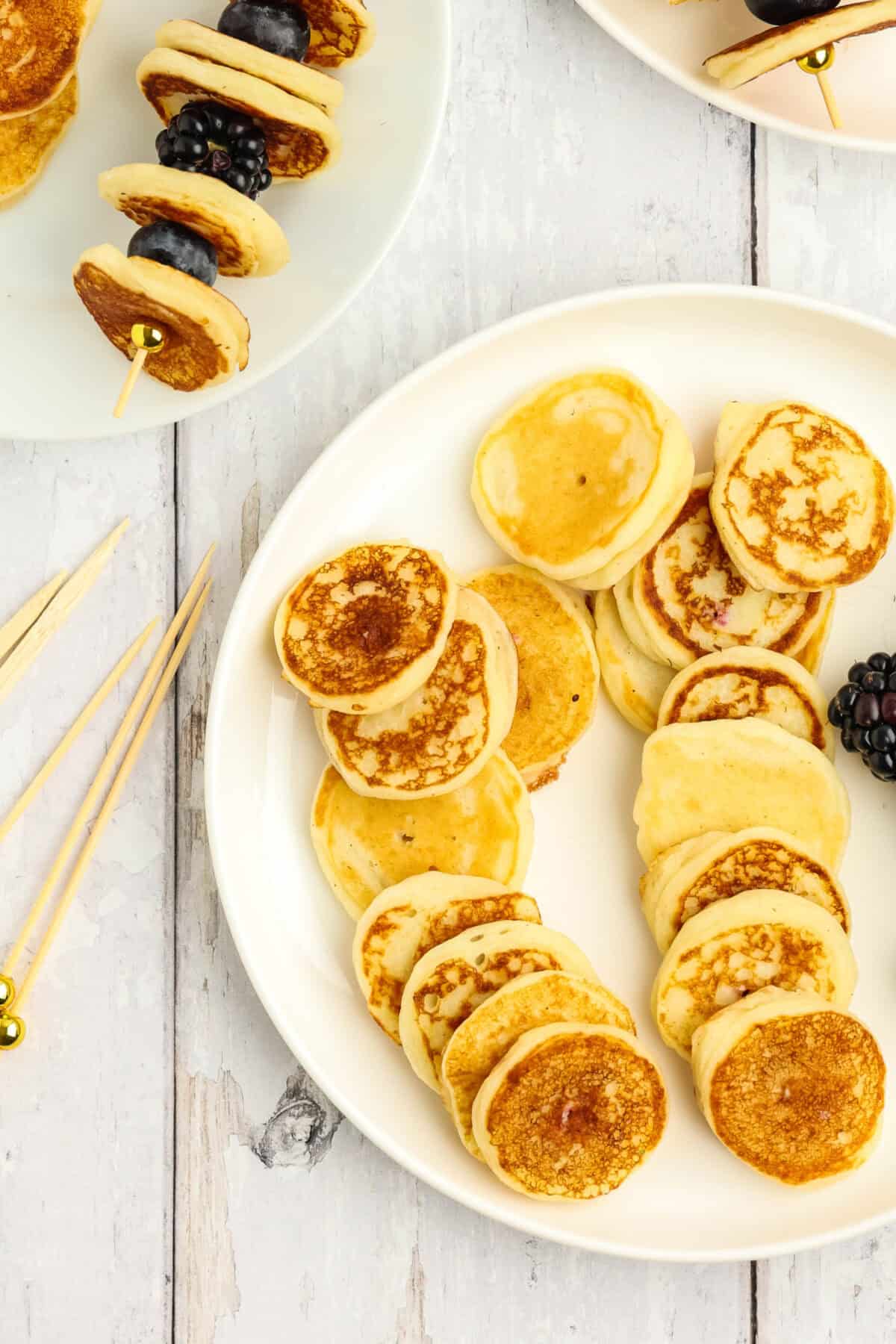 mini pancakes on a plate with skewers next to it