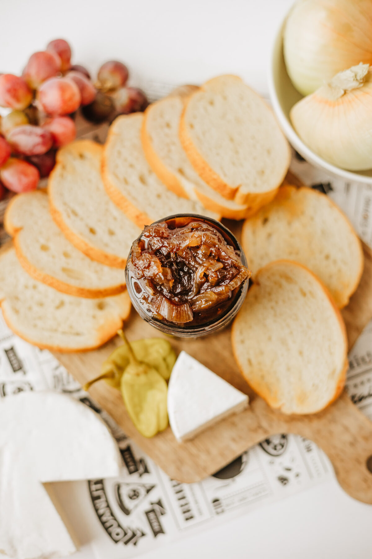 onion jam in a jar surrounded by sliced bread