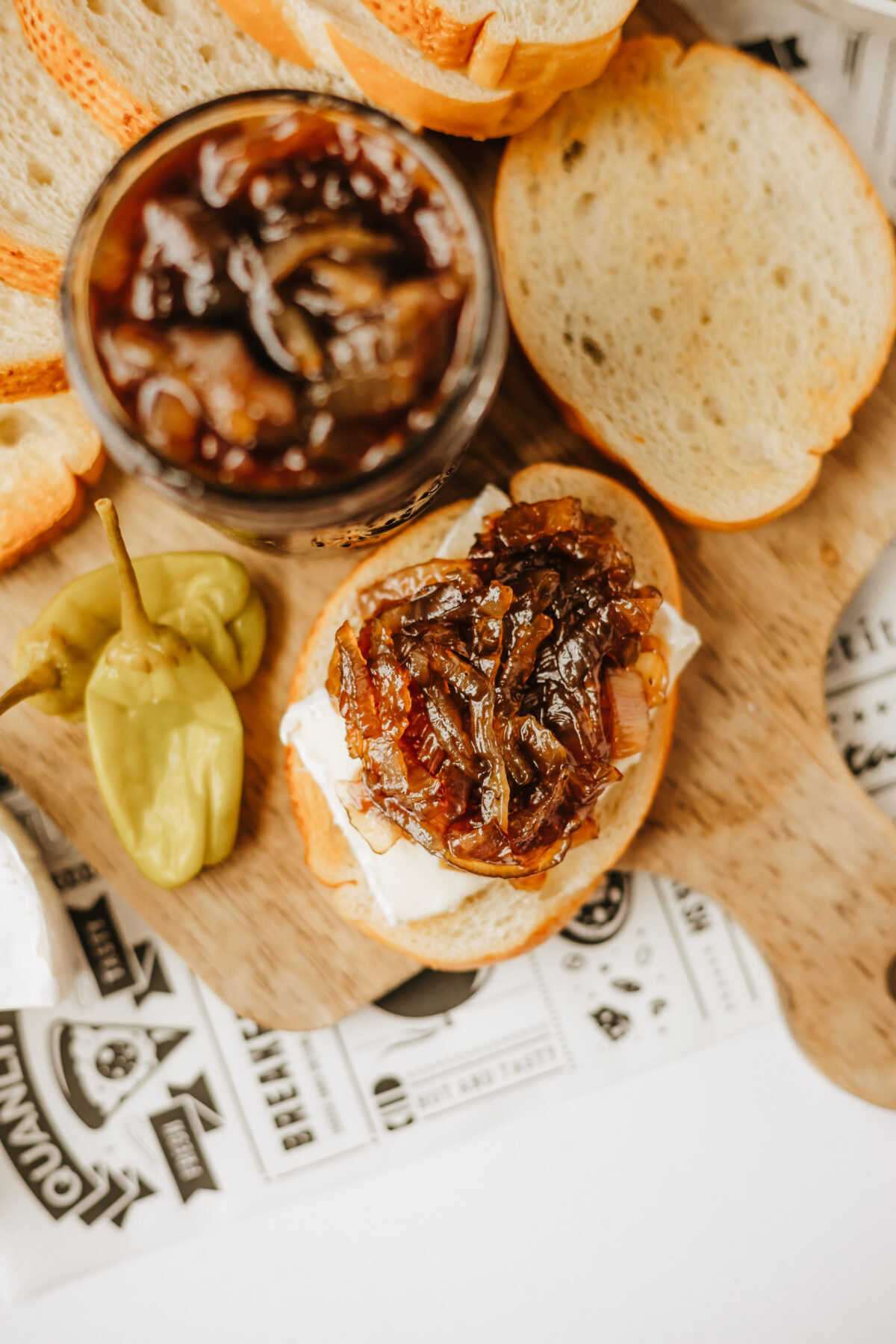 onion jam in a jar surrounded by sliced bread