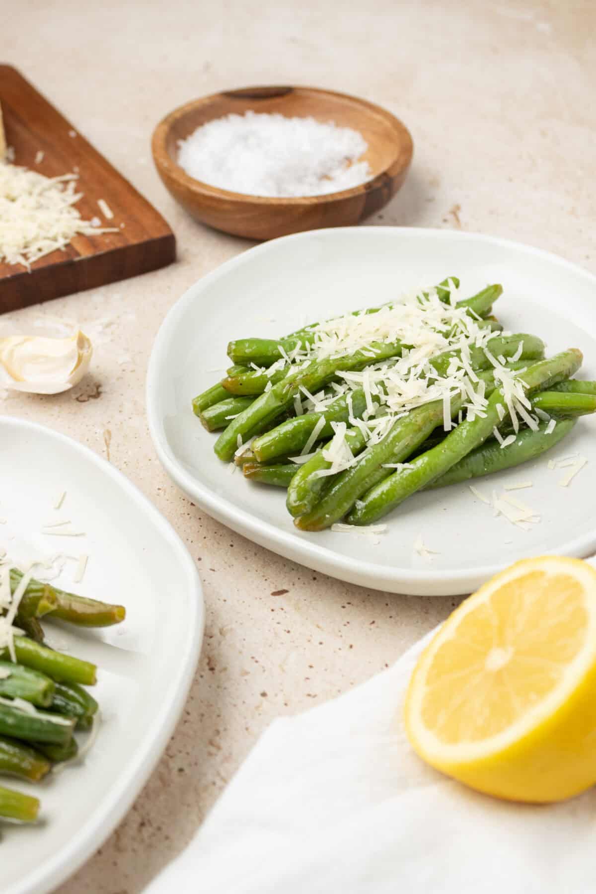 sauteed green beans with shredded parmensan on white plates